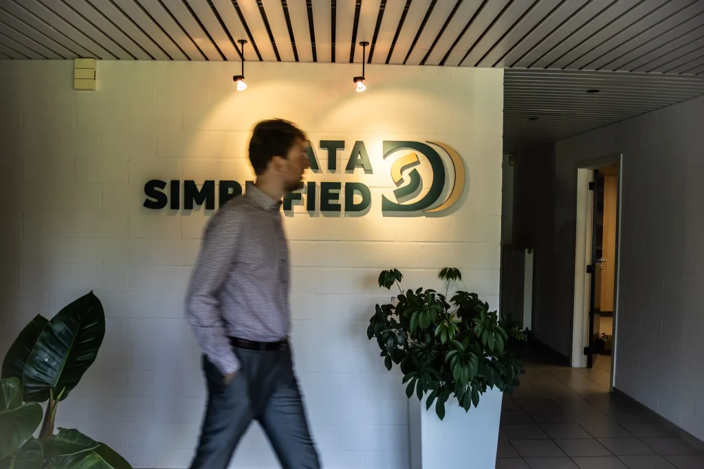 Bavo Vandekeere in de inkom van Data Simplified, voorbijwandelend aan het opgehangen logo