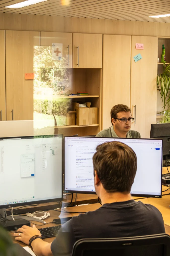 Pieter Pype aan zijn computer met in de achtergrond Jonathan Naert, ook aan zijn computer