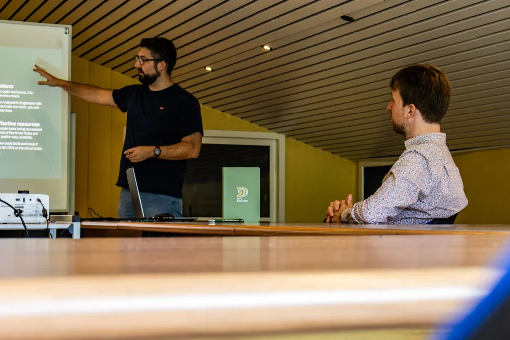 Joeri Leten voor een projectiescherm, Bavo Vandekeere aan het luisteren - home data simplified